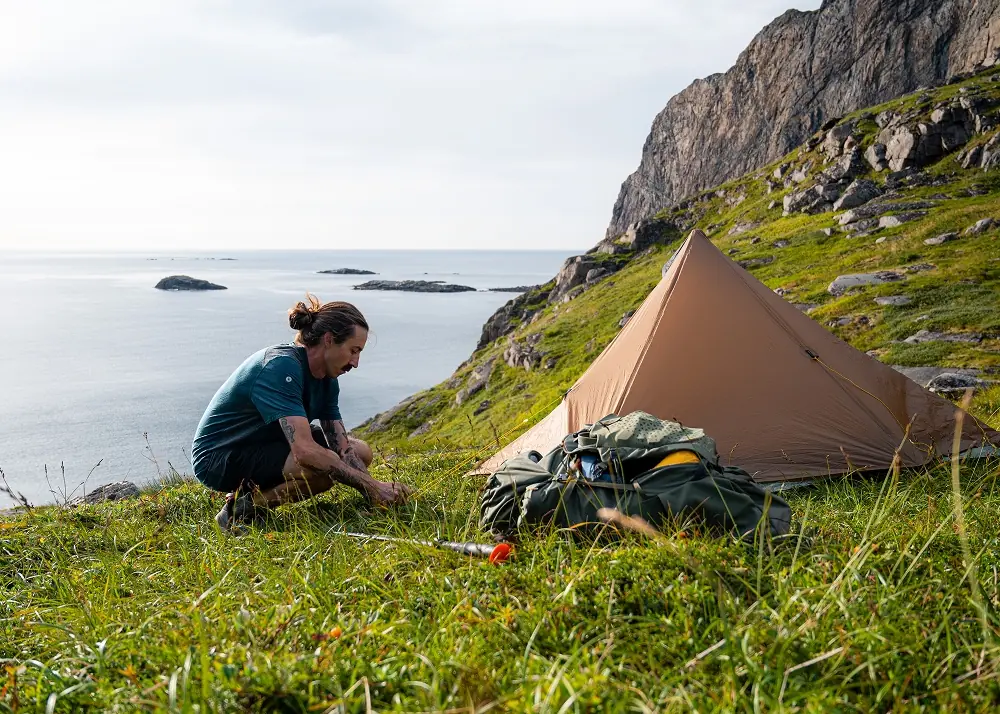 Man setting up tent in the mountains in the summer
